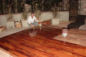 Gente que trabaja en vacaciones. Un ejemplo. Miguel Berrino barniza el deck de la entrada de Petrios.