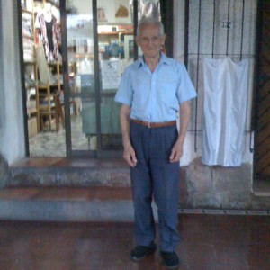 Don Cecidio Conte sale a tomar el fresco a la puerta de su tienda, frente a la estación de servicio.